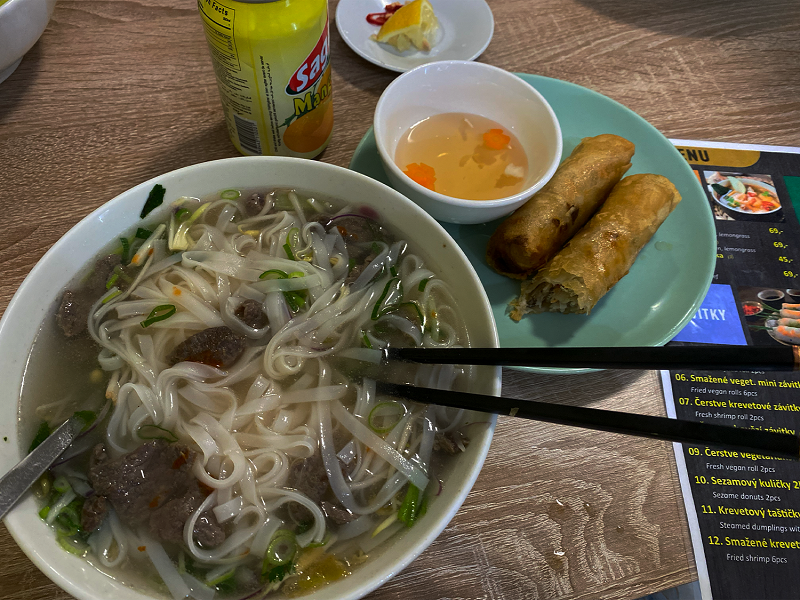 A bowl of pho and two spring rolls on a table