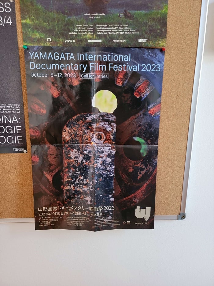 A poster with text that says, "YAMAGATA International Documentary Film Festival 2023" in the FAMU main building on a bulletin board