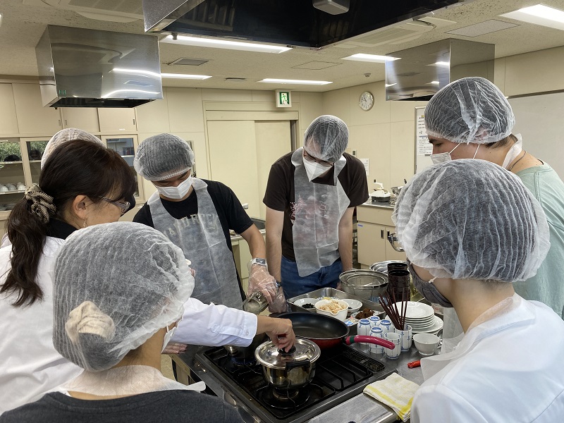 A group of students at CET Japan around a stove in a Japanese cooking workshop