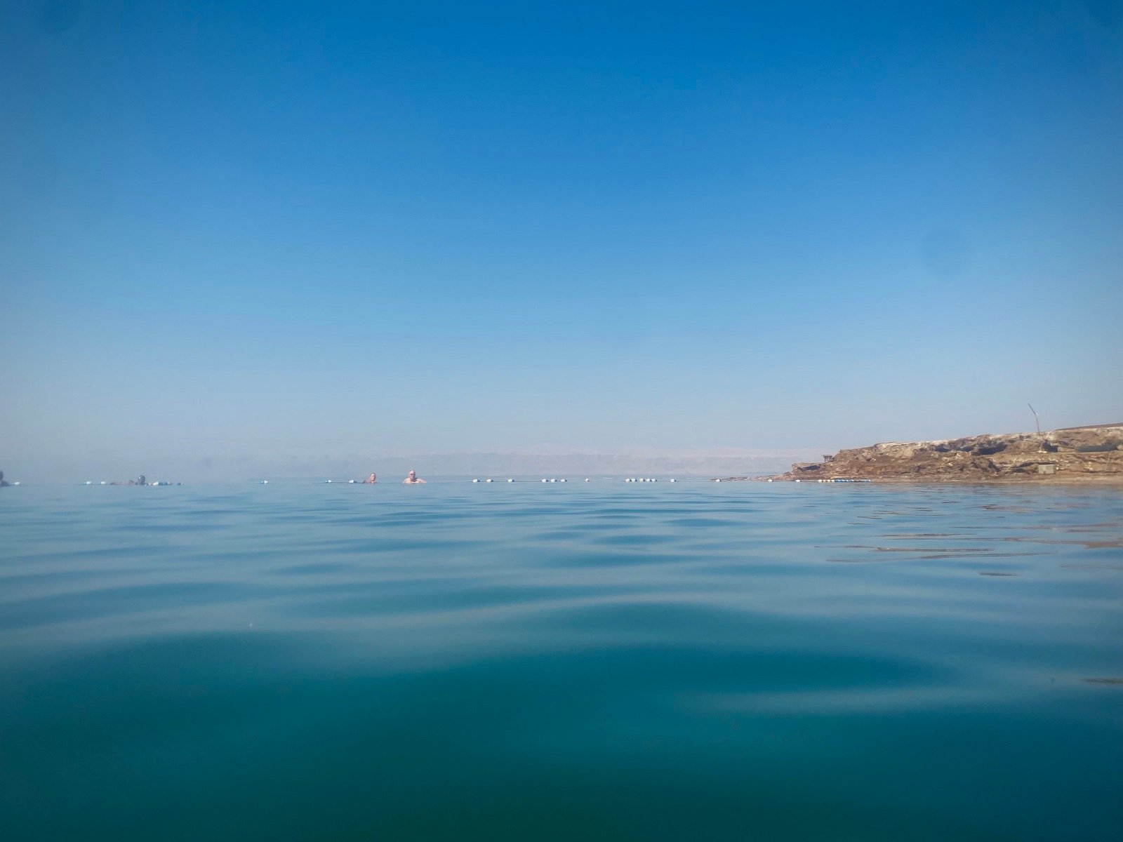Two people in the far distance swimming in the Dead Sea
