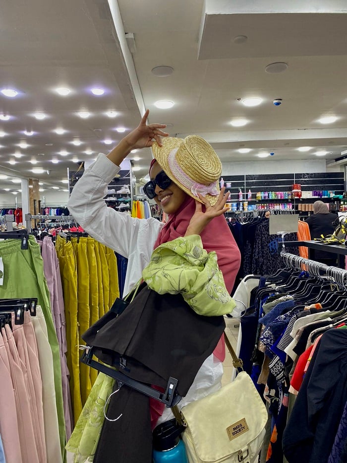 A CET Jordan language partner covering half of her face with a hat while shopping inside a store