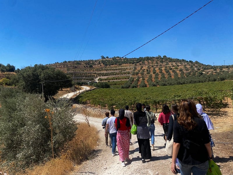 CET Jordan students and their Jordanian neighbors walking outside towards a vineyard
