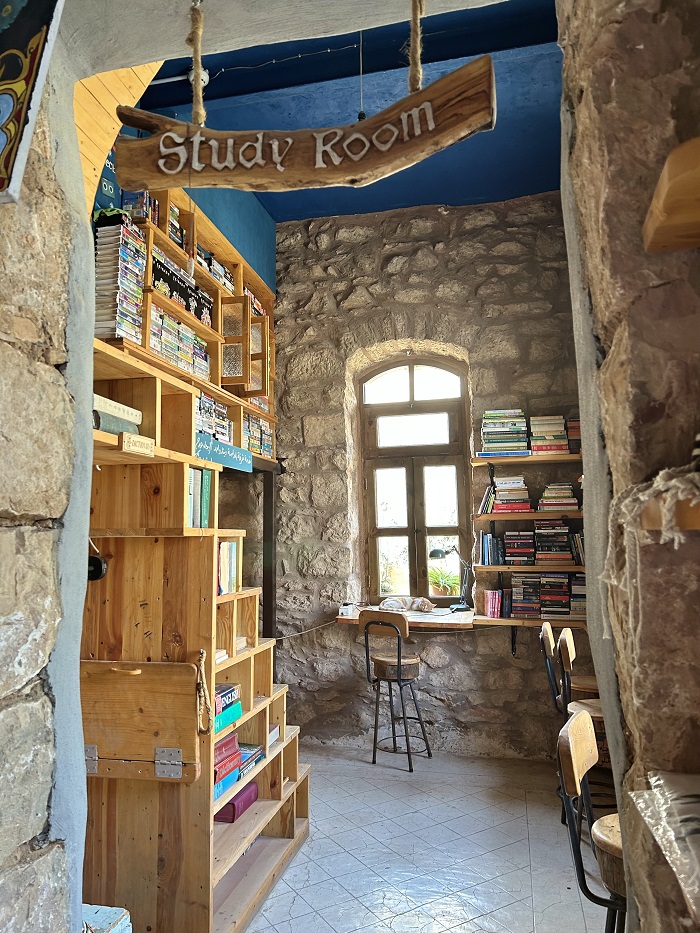 A small study room with many books, a cat, and several chairs in a café called  Kawon’s Kitchen in Madaba, Jordan