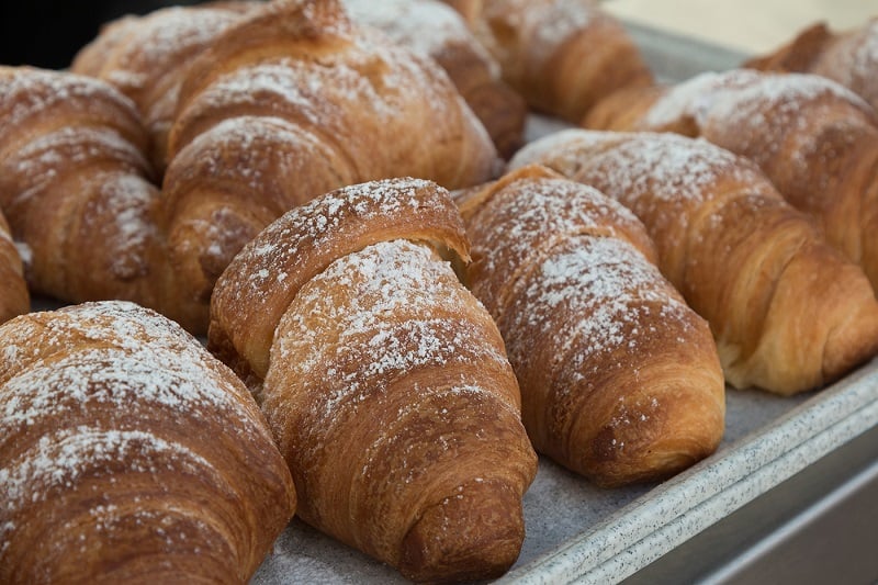 A tray of fresh-baked croissants with powdered sugar sprinkled on top