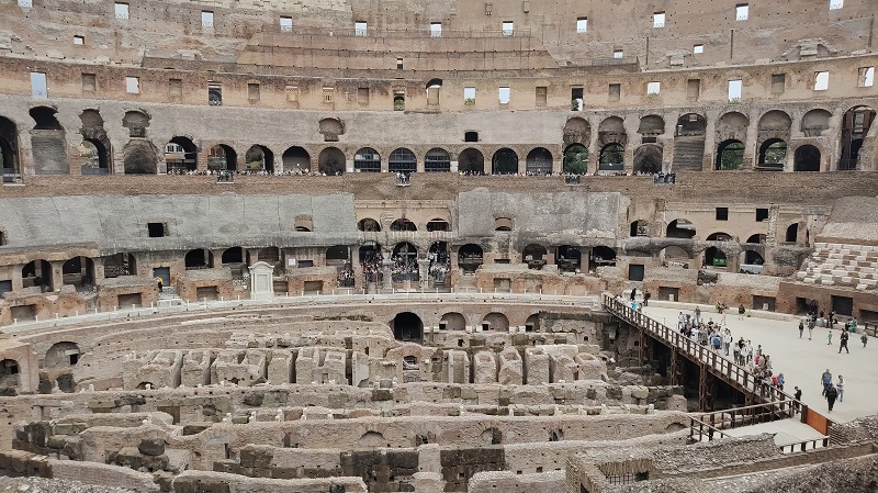 Inside of the Colosseum in Rome, Italy with destroyed or missing parts and people roaming