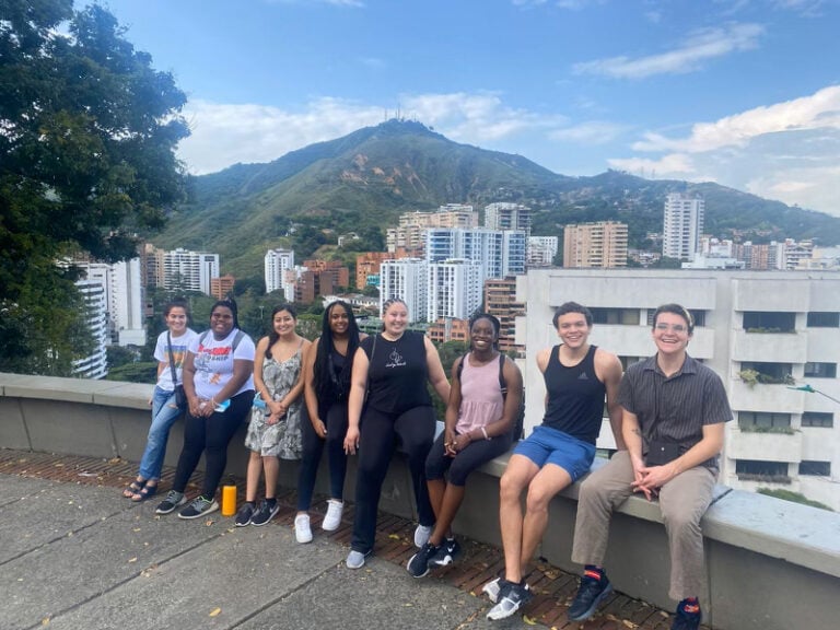 group of students sitting on ledge with city view behind