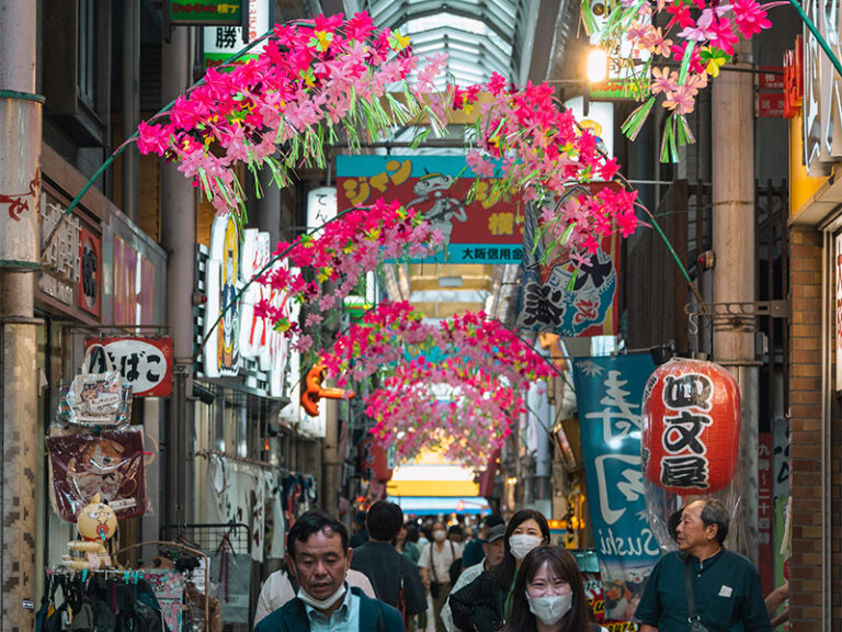 crowded city street with flowers hanging above