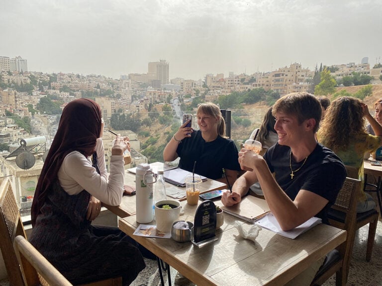 students at lunch with local roommate with view of Amman behind