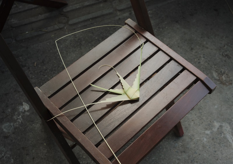 An angel fish made out of palm leaves from locals placed on a wooden chair