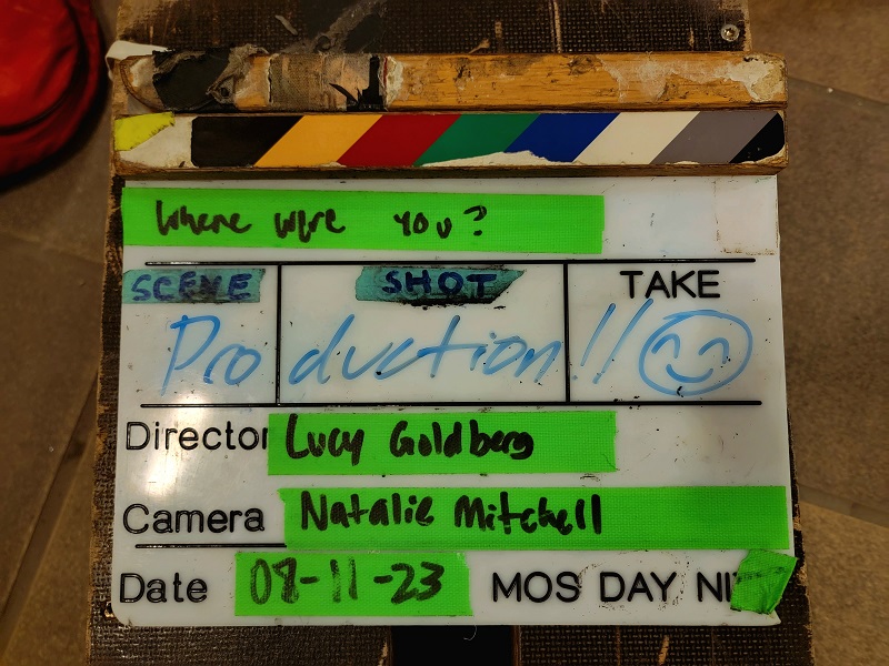 A clapperboard that has "Production" written with a marker and other details about the set and film