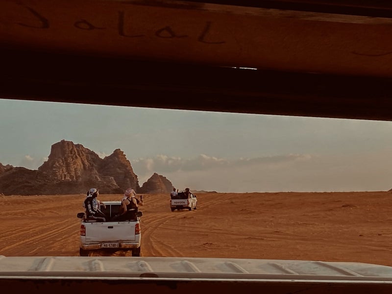 People on trucks riding through the desert of Wadi Rum in Jordan