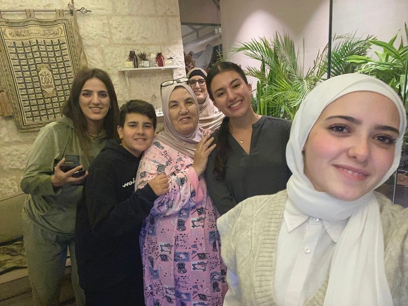 A CET Jordan language partner takes selfie with the CET Jordan student and several members of her family in their home