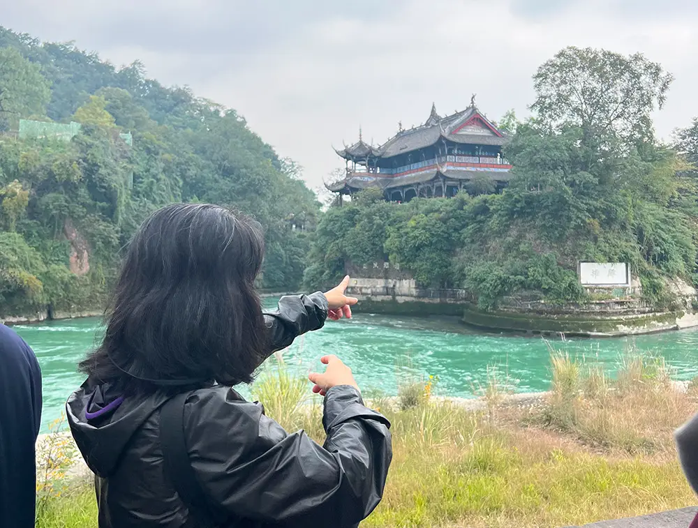 person pointing across lake at temple