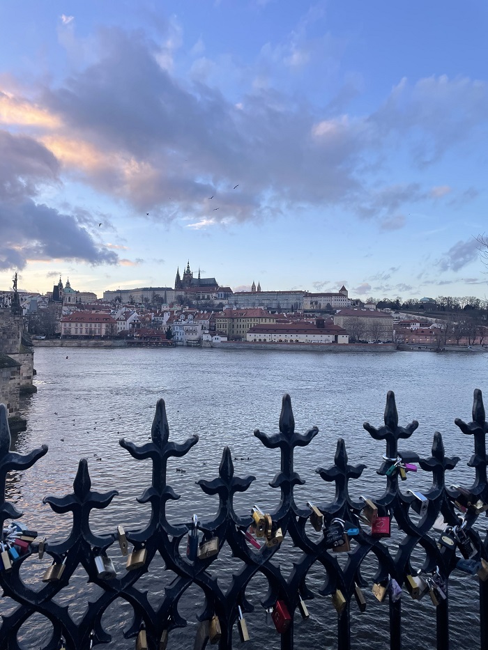 A sunset with a cloudy sky over Charles Bridge with some locks on the bridge bars in Prague, Czech Republic 