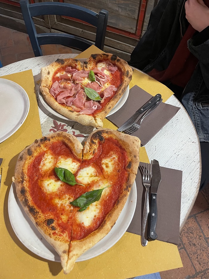 Two heart pizzas alongside utensils on a table from Pizza Napoli 1955 in Florence, Italy