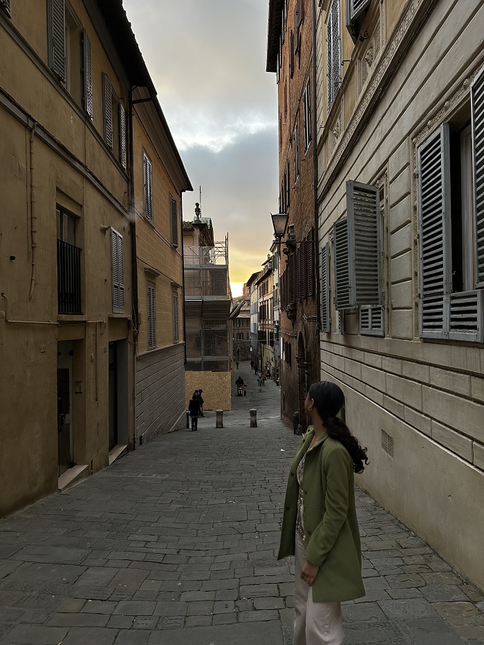 A CET Siena student in the middle of a narrow street in Siena, Italy looking away