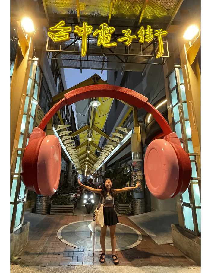 A CET Taiwan student standing in-between a large sculpture of headphones in Taiwan