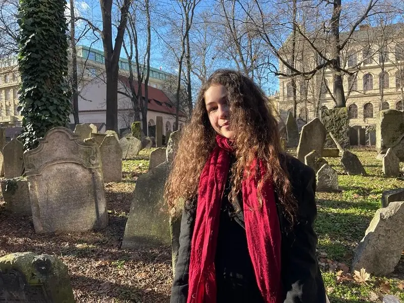A CET Prague student standing admist tombstones in the Old Jewish cemetery, Starý Židovský Hřbitov, in Prague