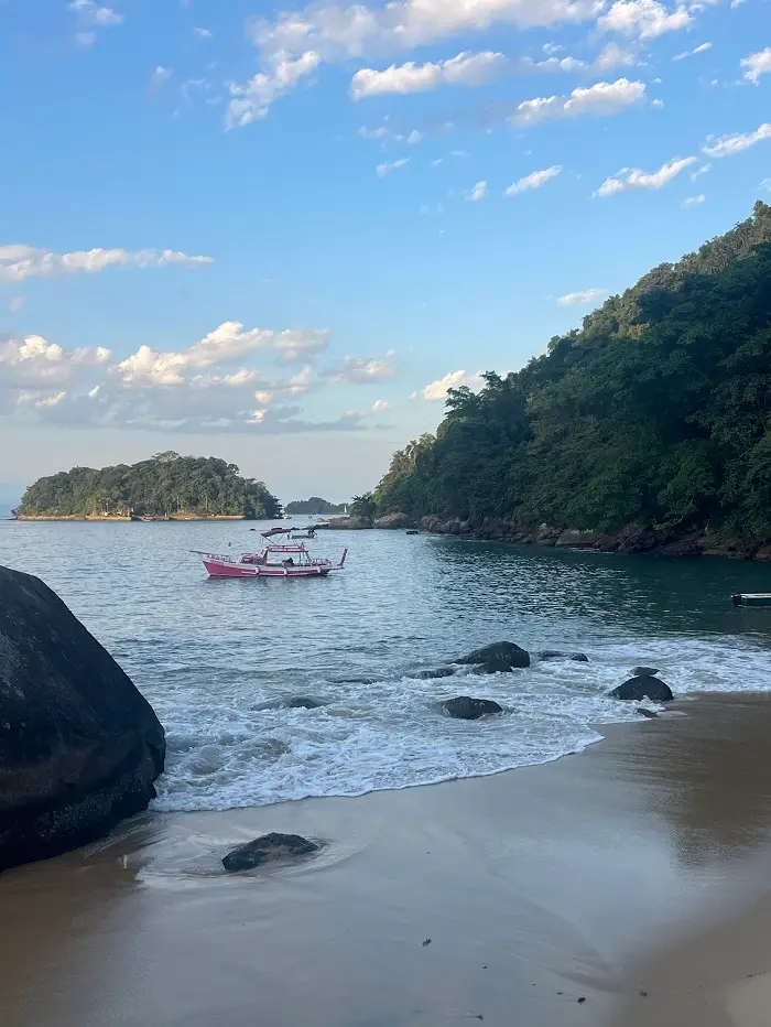 A small pink boat waiting nearby at Praia Vermelha
