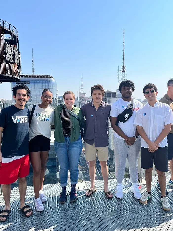 A group of students smiling and posing by Avendia Paulista in São Paulo, Brazil on a cloudless day