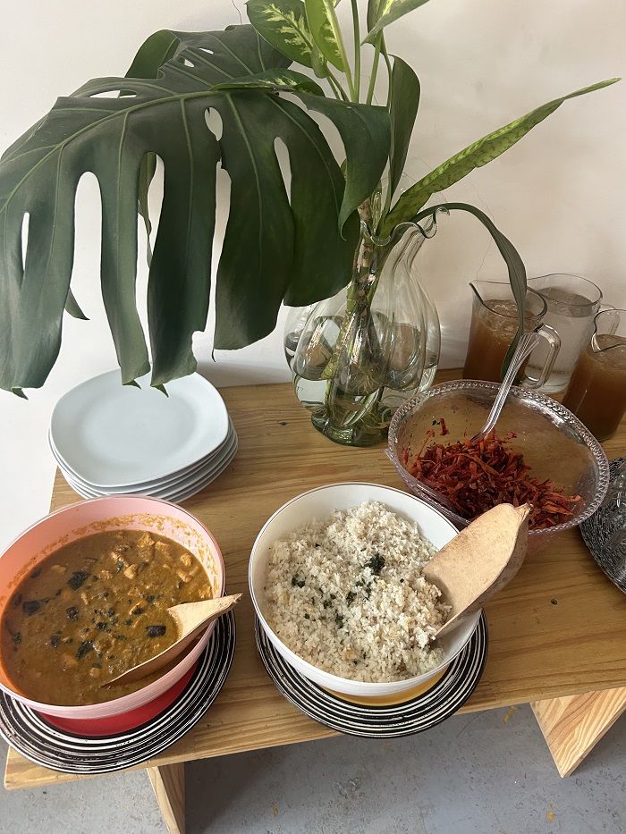 A table with a large bowl of curry, large bowl of rice, and empty plates ready to be served