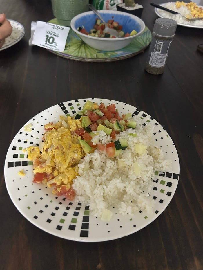 A plate with diced up vegetables, rice, and eggs on a table