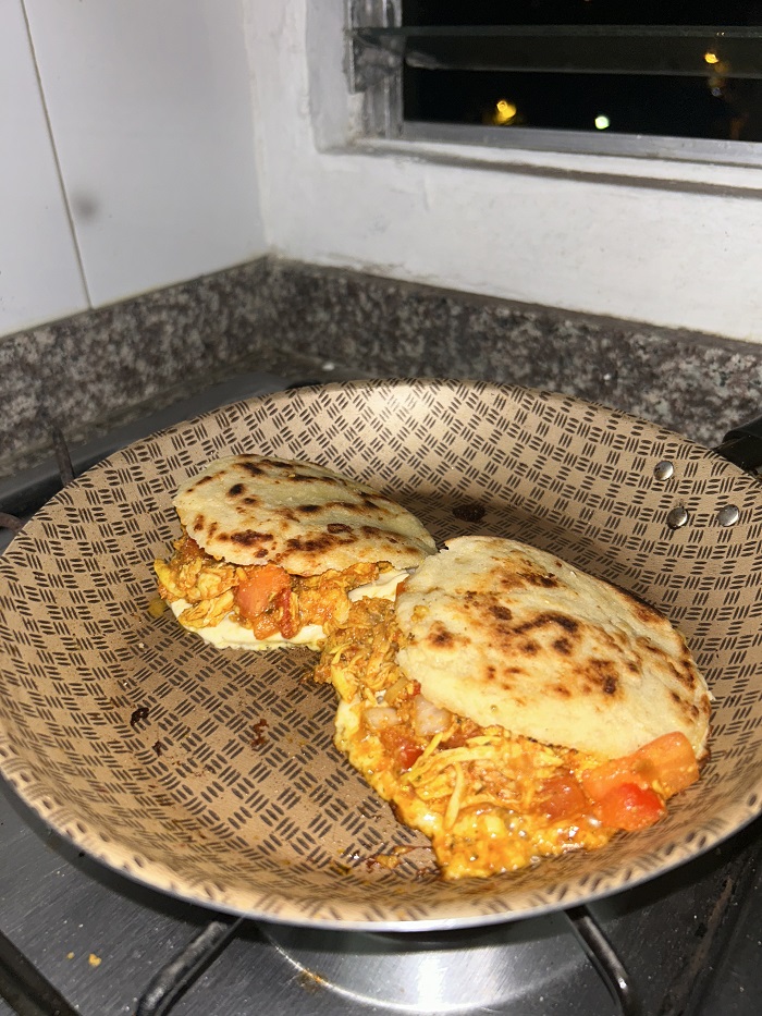 Two arepas stuffed with tomato and chicken on a pan