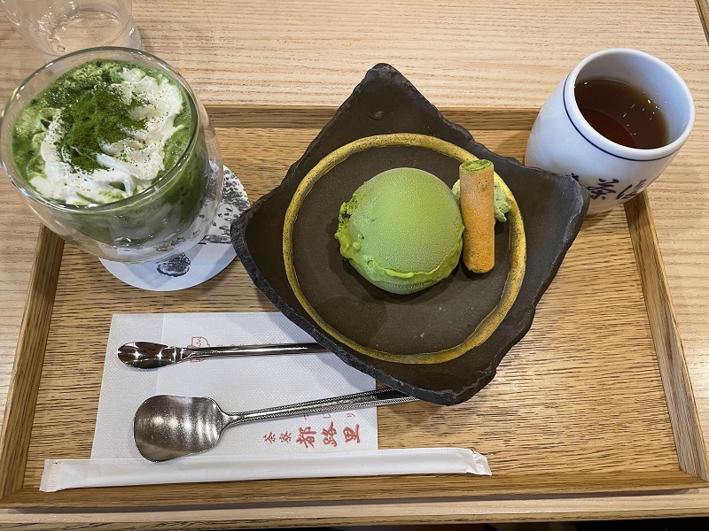 A dessert platter with a matcha latte, matcha ice cream, green tea and utensils