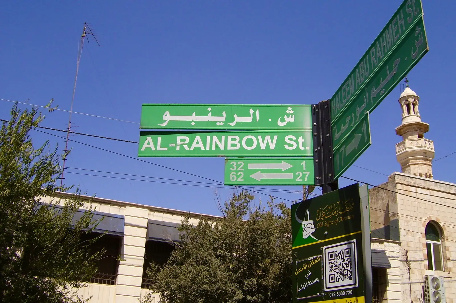The Rainbow Street sign written in Arabic and English with a view of Safadi Masjid in the background