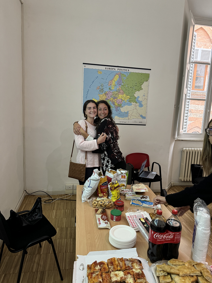 A CET Siena student hugging a local roommate with Italian snacks laid out on a table in a classroom