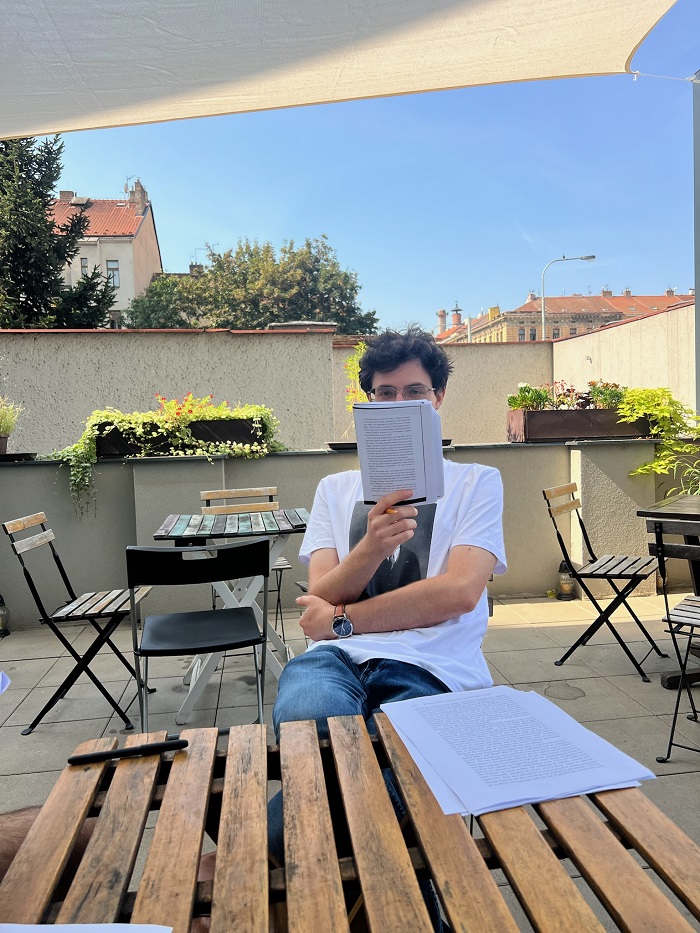 A CET Prague student holding up papers and reading outside