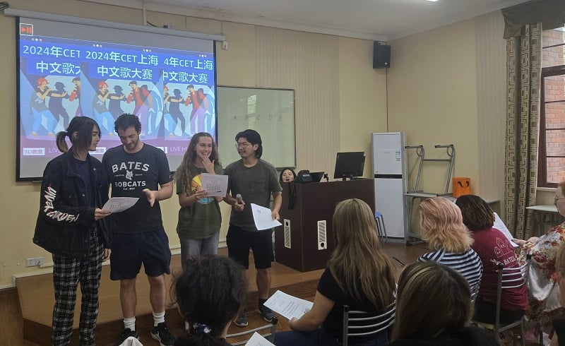 A group of four CET Shanghai students singing in front of a classroom