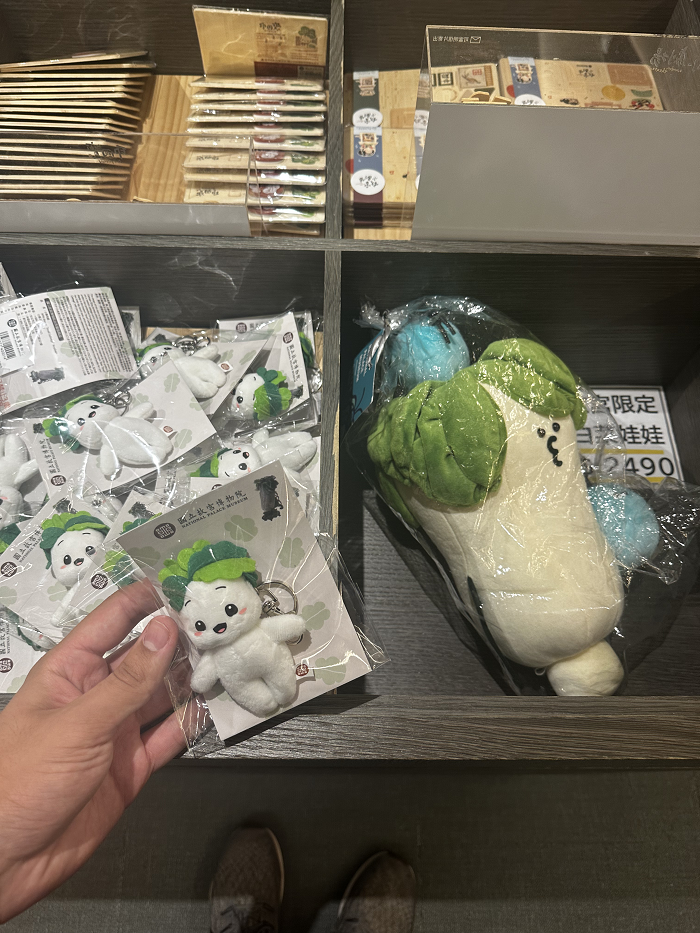 A hand holding a little keychain of the Jadeite Cabbage mascot