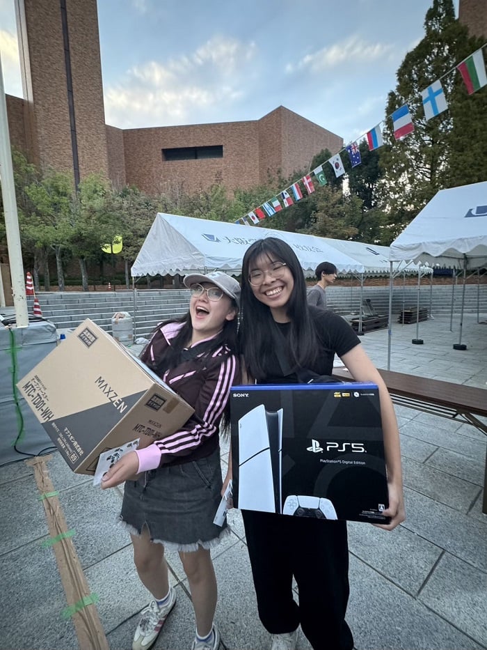 Two CET Japan students holding prizes while standing outside on Osaka Gakuin University's campus 