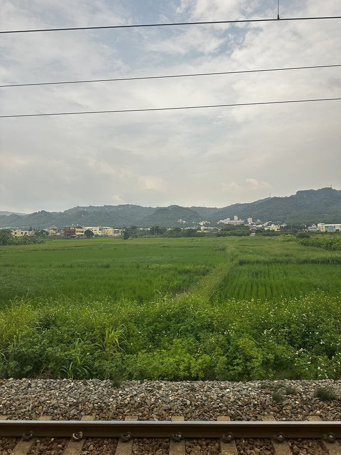 A view of rolling hills and fields of Taiwan's countryside from the inside of a train