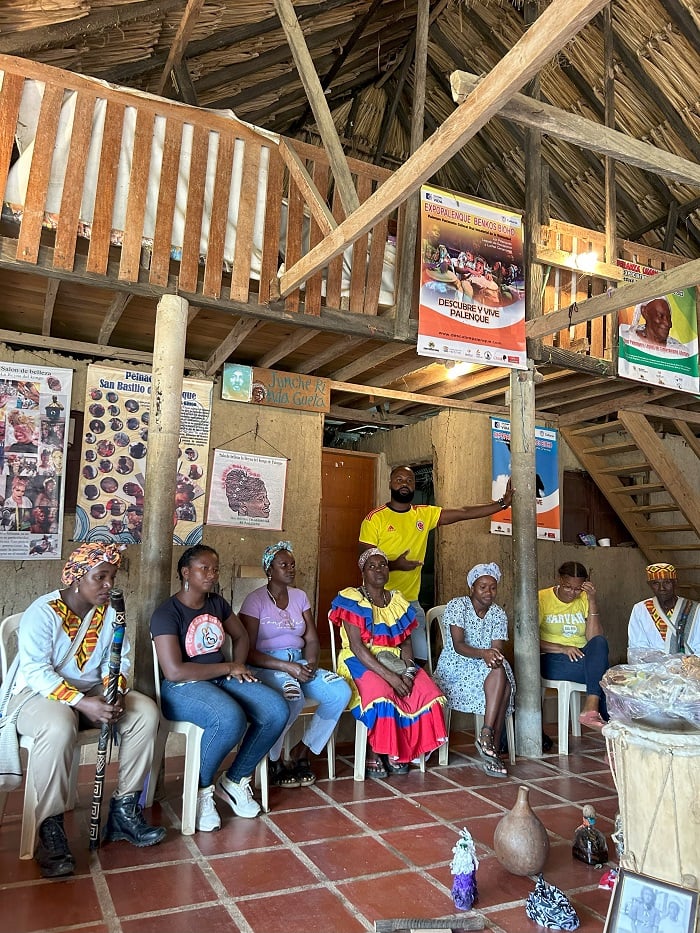 A row of local women from San Basilio de Palenque sitting in chairs while talking to CET Colombia students