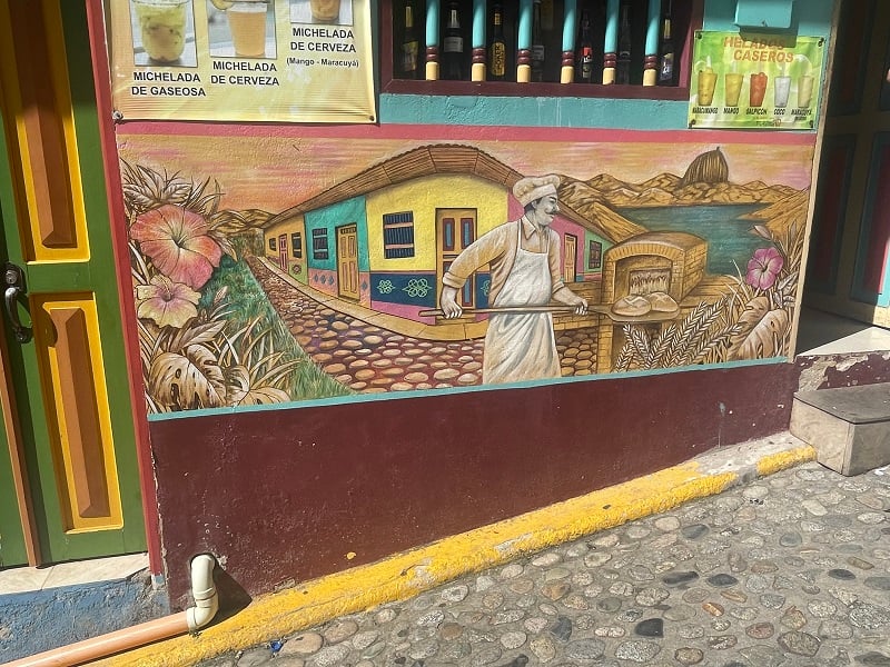 A mural of a baker putting bread inside an oven in the streets of Medellín, Colombia