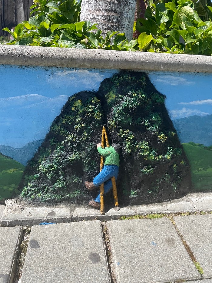 Wall art of a person climbing the large granite rock, called Piedra del Peñol, in Medellín, Colombia