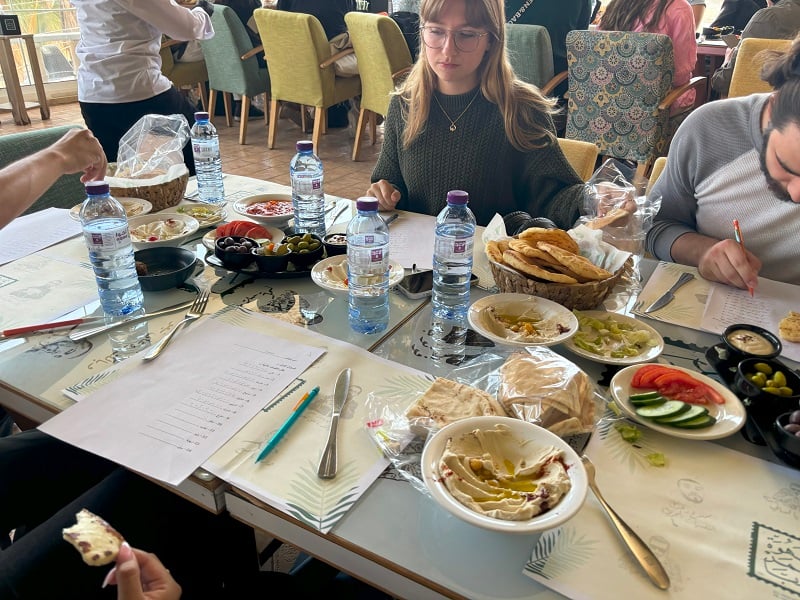 People sitting around a table working on homework and eating bread with dips and vegetables