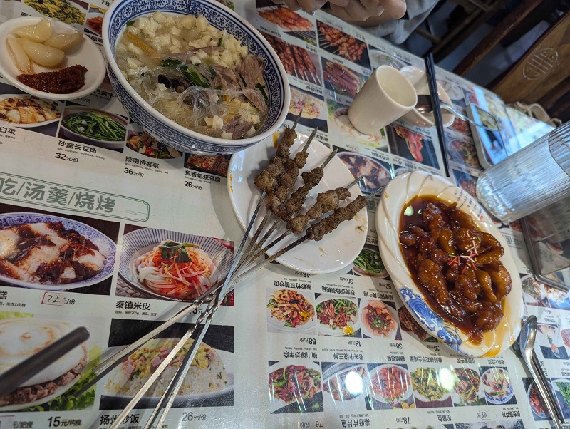 Foods on a table including noodles, meat skewers, and marinated meats from the region of Xi'An