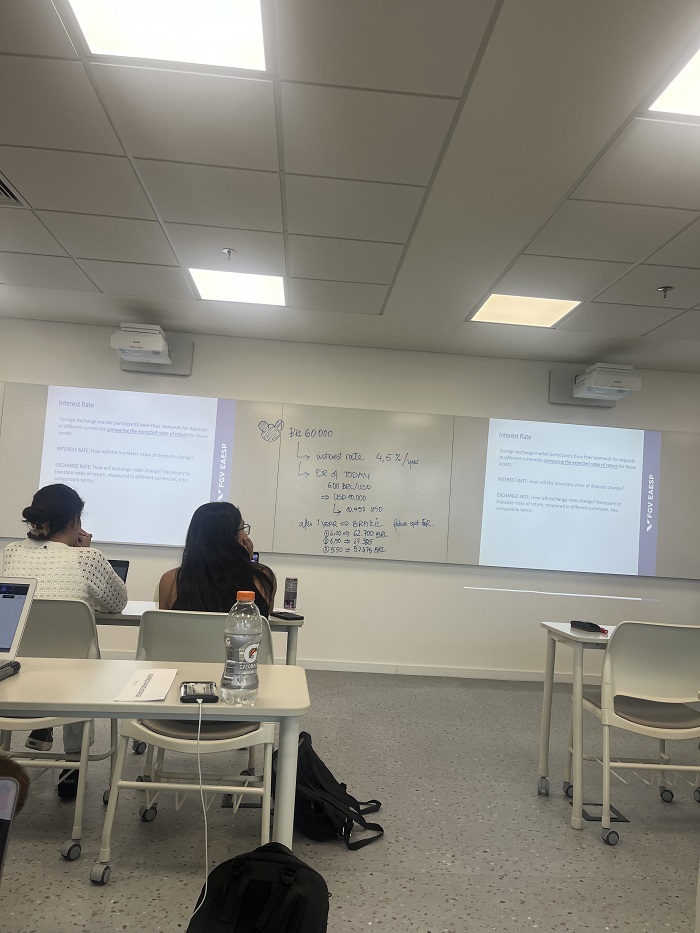 Students sitting in a classroom looking at writing on a large whiteboard in the front of the classroom