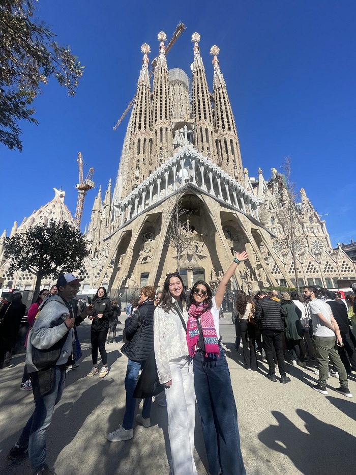 Two CET students posing and standing outside of La Sagrada Familia on a cloudless day