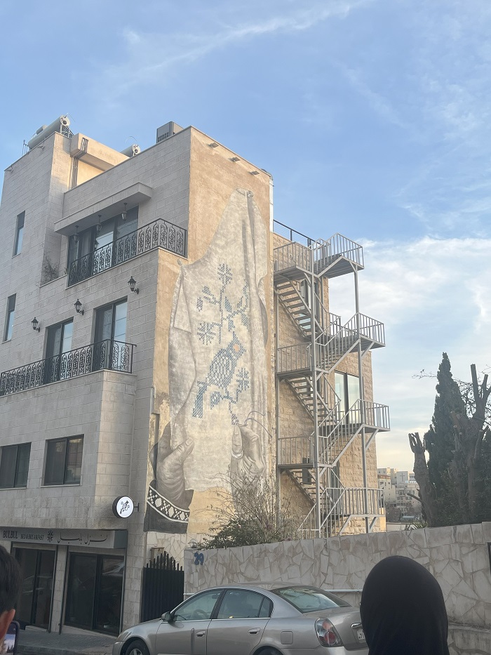 Graffiti of a handing holding up a piece of cloth on the side of a building in Amman, Jordan