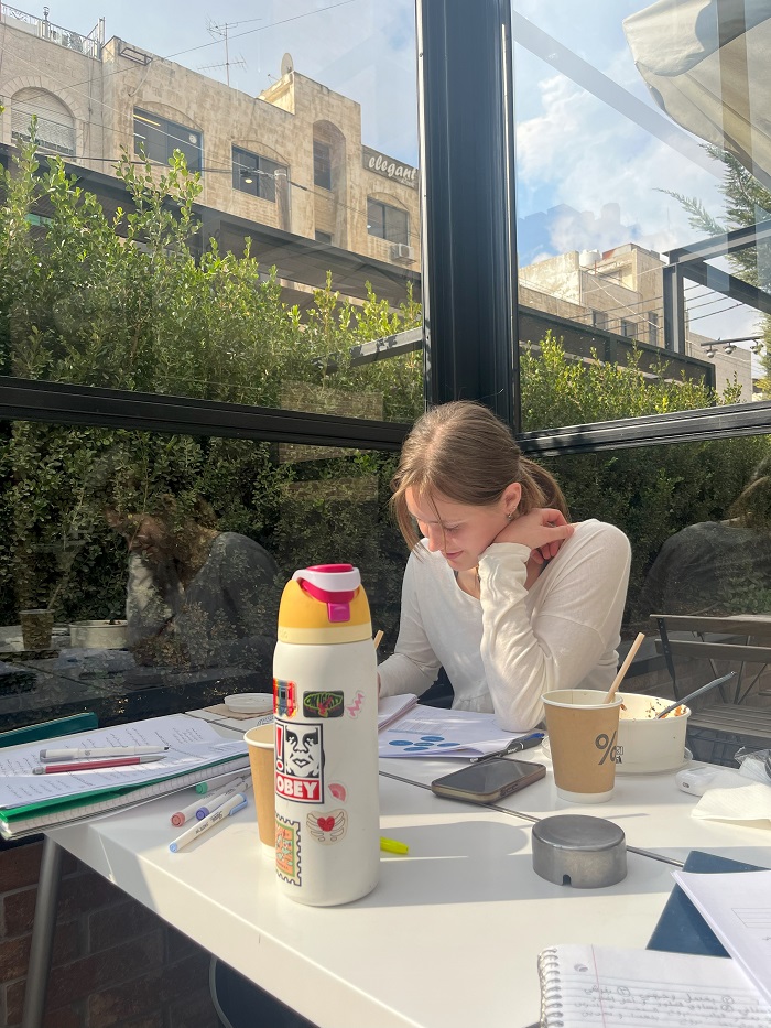 A CET Jordan student studying while sitting by a window in a café