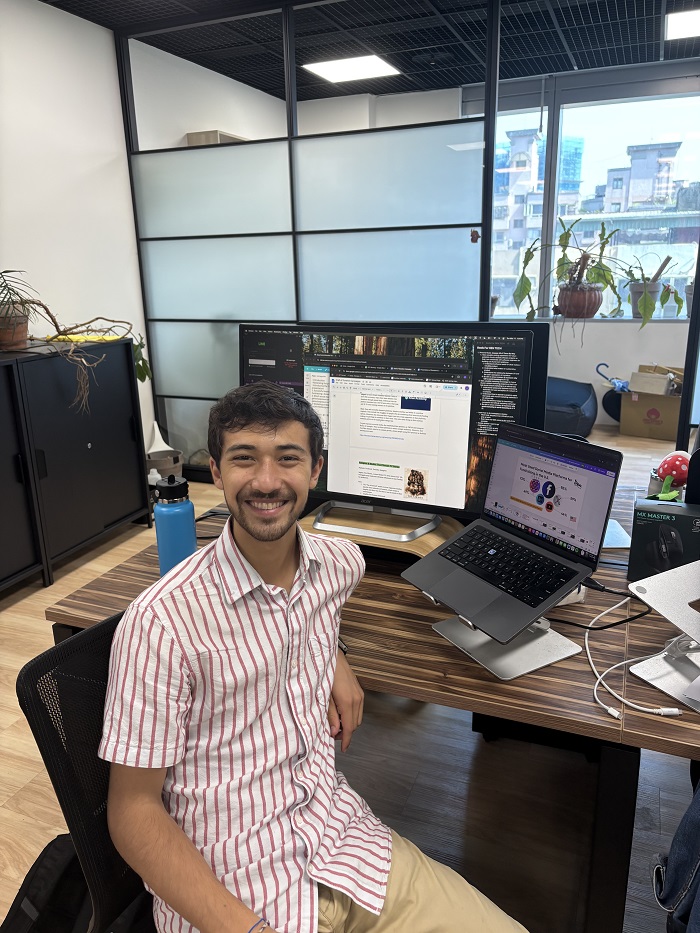 A CET Taiwan student sitting on a chair by his internship desk with a monitor