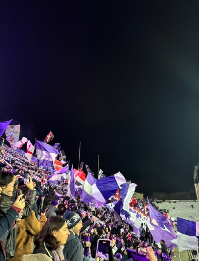 A crowd holding up flags while at a Fiorentina game in Florence, Italy
