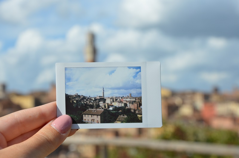 A hand holding up a polaroid of the city of CET Siena