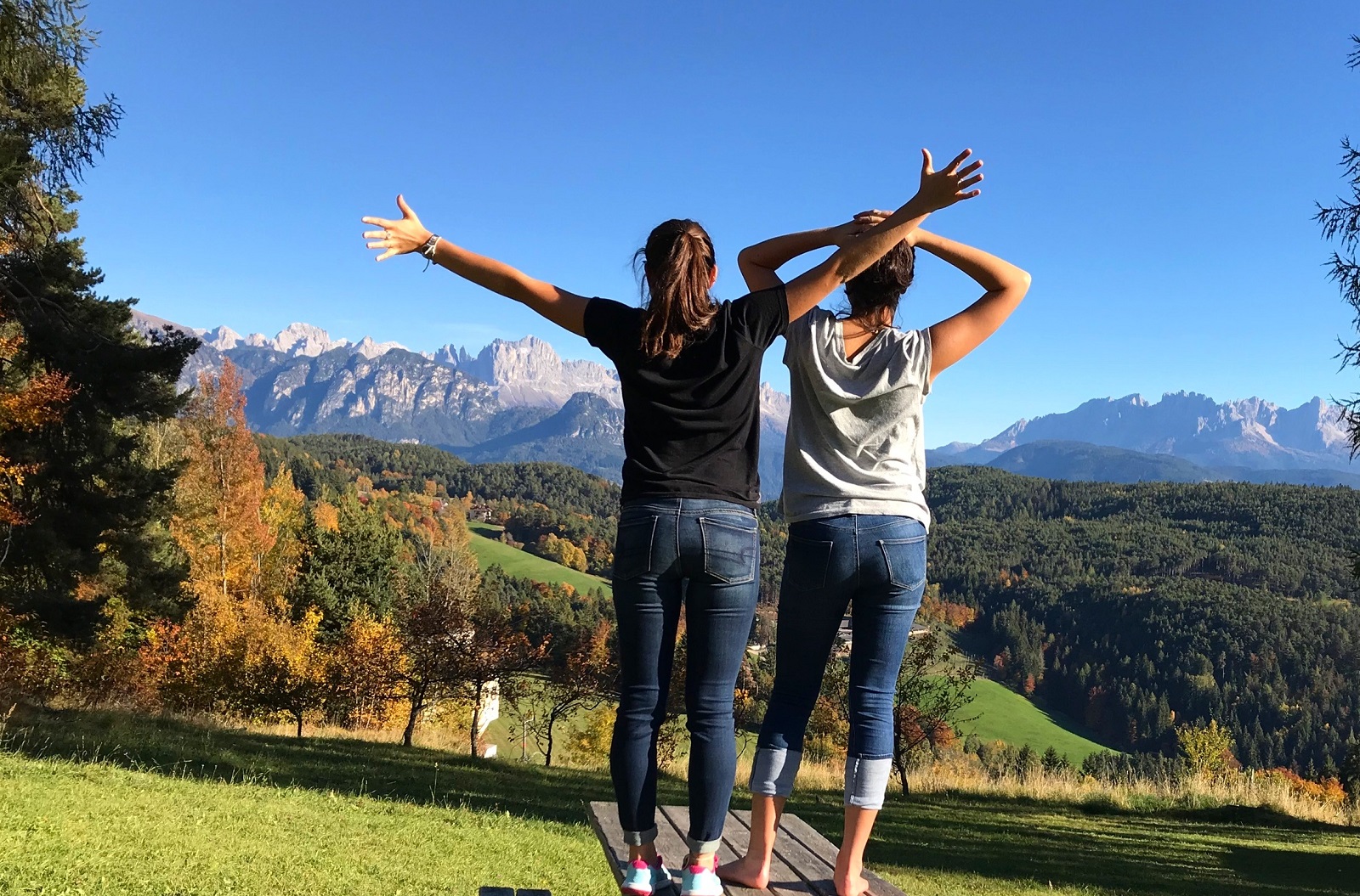 Two CET students stretching their arms wide and looking towards the Dolomite Mountains in Italy
