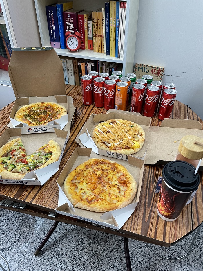 A table filled with canned Colas and Domino pizzas in boxes