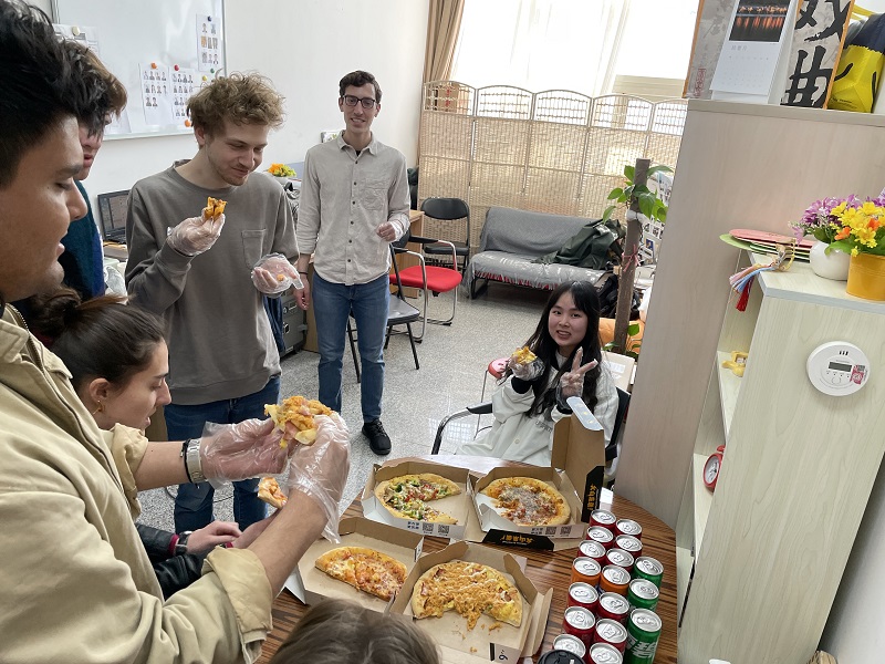CET study abroad students eating pizza together in a room